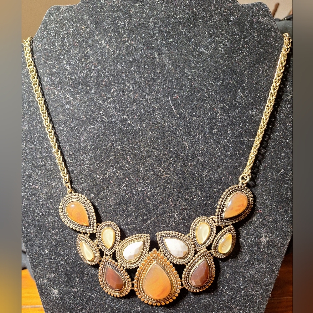 Gold colored necklace with brown and white stones.